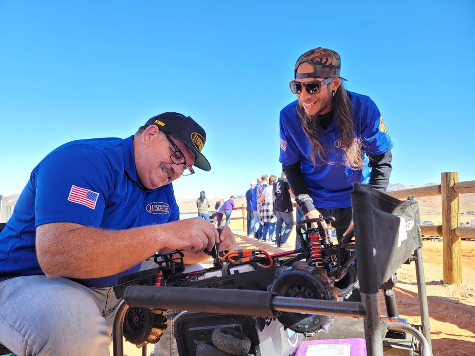 Two O11C members working on an RC crawler together at an outdoor event