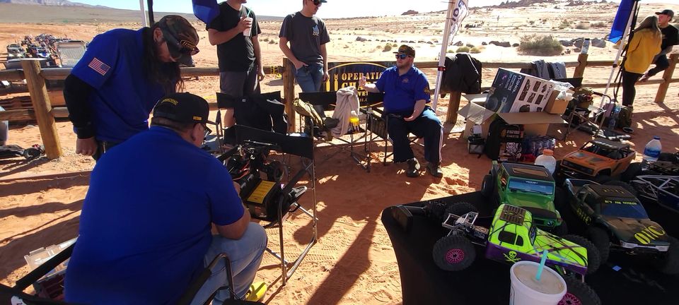 O11C members under their event tent with RC trucks on the tables